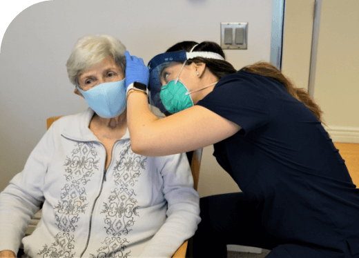 Elderly woman wearing mask having her ears checked